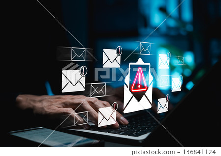 Email phishing alert and cybersecurity threat detection concept. Hands typing on laptop with warning icons and suspicious email symbols representing email scams, spam mail, data breach, hacking risks, 136841124