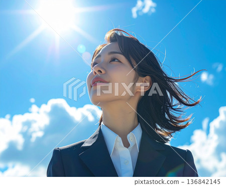 A woman in a suit looking up at the sky, stepping into the future 136842145