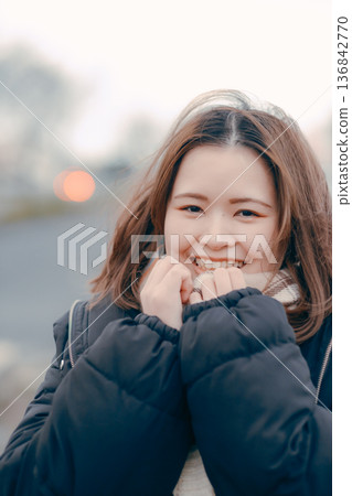 冬日傍晚，一位沉思的年輕女子在戶外的肖像照 136842770