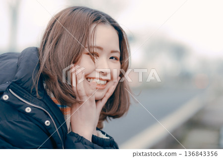 A Japanese woman in her twenties lost in thought in a winter city 136843356