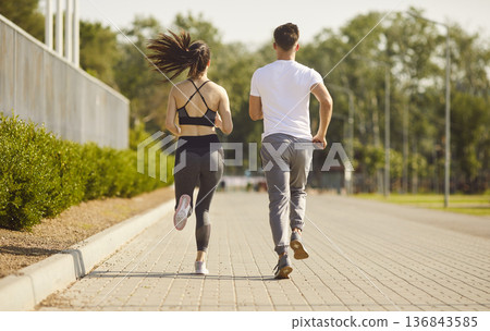 Couple running together on path under sunlight, outdoor exercise, moving for health and fitness 136843585