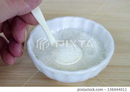 op view of salt mixture in white bowl with spoon representing balanced sodium intake and preventive healthcare message. op view of salt mixture in white bowl with spoon representing balanced sodium intake and preventive healthcare message. 136844011