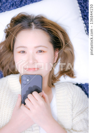 A Japanese woman in her twenties holding a smartphone at home A Japanese woman in her twenties holding a smartphone at home 136844150