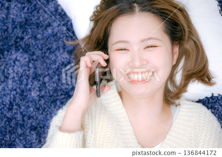 A Japanese woman in her twenties making a smartphone call at home A Japanese woman in her twenties making a smartphone call at home 136844172