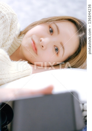 A Japanese woman in her twenties looking at her smartphone at home A Japanese woman in her twenties looking at her smartphone at home 136844236