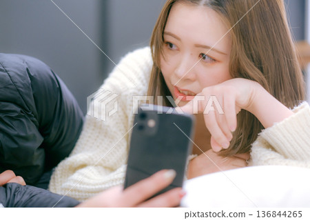 一位二十多歲的日本女性在家中看著她的智慧型手機 一位二十多歲的日本女性在家中看著她的智慧型手機 136844265