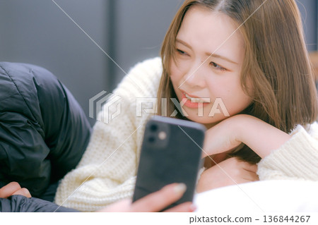 A Japanese woman in her twenties looking at her smartphone at home A Japanese woman in her twenties looking at her smartphone at home 136844267