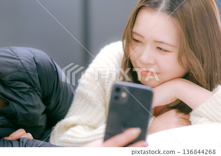 A Japanese woman in her twenties looking at her smartphone at home A Japanese woman in her twenties looking at her smartphone at home 136844268