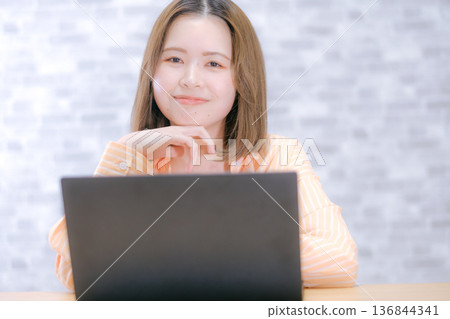 A Japanese woman in her twenties worried while looking at a laptop computer A Japanese woman in her twenties worried while looking at a laptop computer 136844341