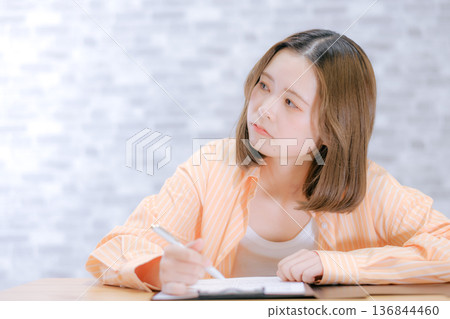 A Japanese woman in her twenties studying at a desk 136844460