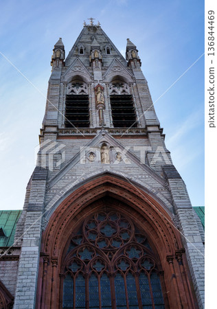 A striking view of a church tower in Dublin, Ireland, showcasing its intricate architecture against a clear sky. 136844469