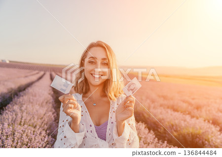 Lavender field portrait woman holding photos of herself smiling in a blooming flower farm at sunset 136844484
