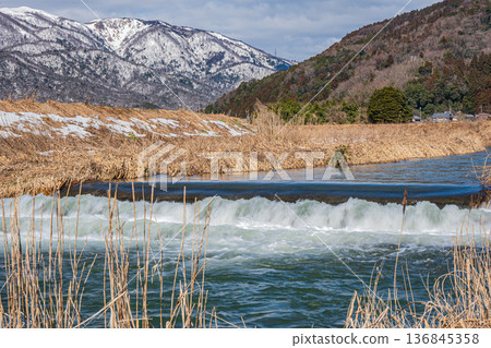 Chiuchi River in early spring and the Nosaka Mountains with remaining snow. Makino Town, Takashima City, Shiga Prefecture 136845358