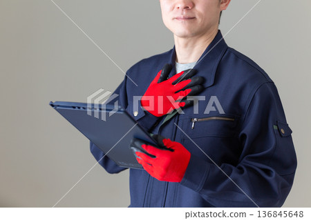 A middle-aged male businessman in work clothes holding a binder and putting his hand on his chest A middle-aged male businessman in work clothes holding a binder and putting his hand on his chest 136845648