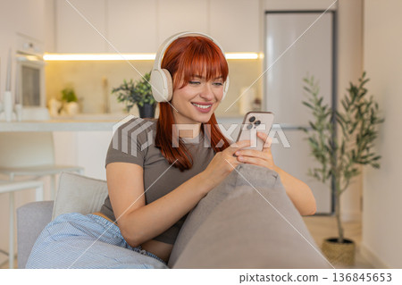 Young woman with headphones enjoys music from smartphone relax unwind breathing calm soft smile vibe Young woman with headphones enjoys music from smartphone relax unwind breathing calm soft smile vibe 136845653
