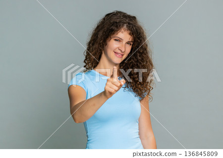 Young woman pointing finger directly at camera smiling confidently indicating personal message 136845809