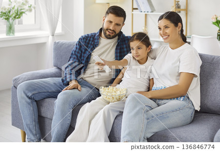 Happy family watching movie at home on sofa with popcorn and remote control 136846774