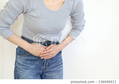 一位女士的手，她感到下腹部疼痛。畫面顯示她身體狀況不佳。 136846811