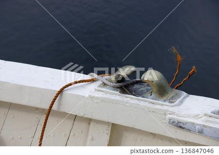 Rope tied on metal cleat on wooden boat 136847046