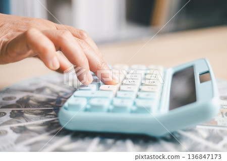 Close-up of a hand pressing calculator keys for budgeting, accounting and financial analysis. Business expense planning, tax calculation, office desk background, copy space for paperwork. Close-up of a hand pressing calculator keys for budgeting, accounting and financial analysis. Business expense planning, tax calculation, office desk background, copy space for paperwork. 136847173