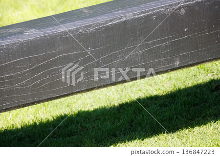 Abstract close-up of black wooden paddle on grass by canal lock Abstract close-up of black wooden paddle on grass by canal lock 136847223