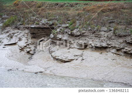 Water outlet pipe in muddy riverbank 136848211