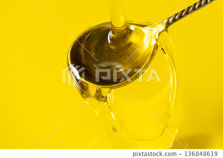 Olive oil flow into spoon, oil dripping from spoon, macro texture, frozen movement Olive oil flow into spoon, oil dripping from spoon, macro texture, frozen movement 136848619