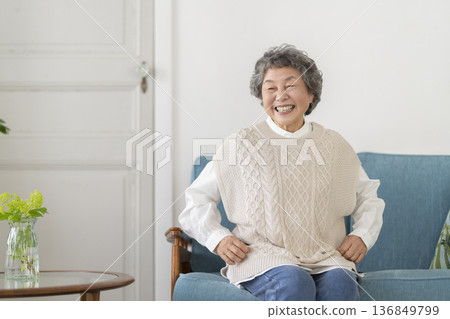 Smiling senior woman sitting on sofa Smiling senior woman sitting on sofa 136849799
