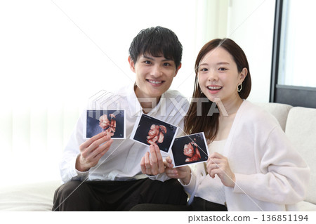 Couple holding ultrasound photo 136851194
