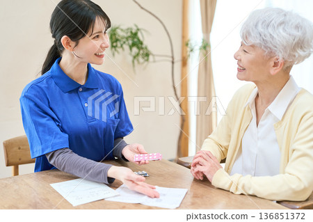 亞裔護理員在家庭護理探訪期間協助病人服藥 136851372