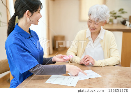 亞裔護理員在家庭護理探訪期間協助病人服藥 136851378