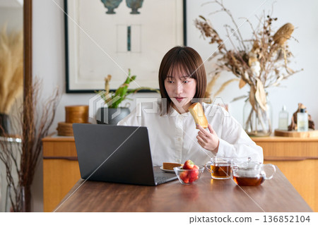 一名婦女一邊工作一邊吃麵包 一名婦女一邊工作一邊吃麵包 136852104