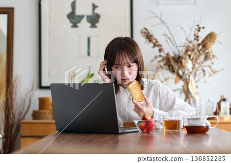 一名女子一邊工作一邊吃早餐 一名女子一邊工作一邊吃早餐 136852285