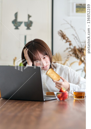 一名女子一邊工作一邊吃早餐 一名女子一邊工作一邊吃早餐 136852289