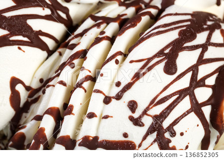 Pats of ice-cream with chocolate syrup. Pats of ice-cream with chocolate syrup. 136852305