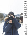 A woman holding a camera in a snowy cityscape - Winter travel snaps 136852963