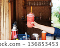Hand holding fresh watermelon smoothie in plastic glass of cafe in Thailand 136853453