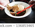 Hand holding Chicken thighs of Noodles with braised chicken in white bowl 136853465
