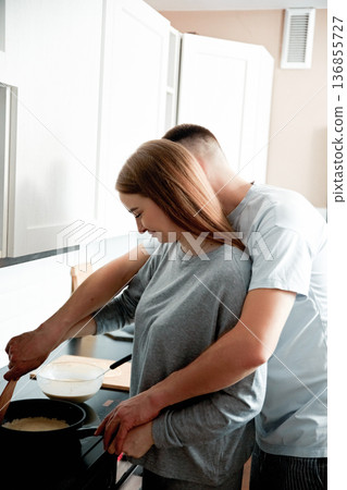 Couple cooking pancakes together at home kitchen 136855727