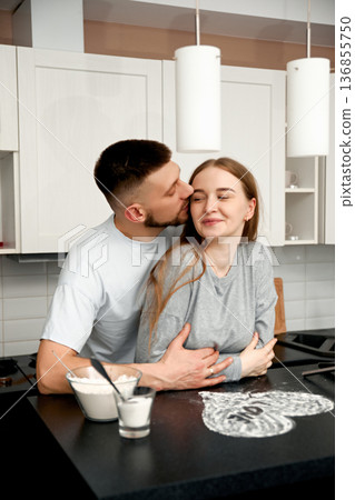 Couple cooking together and hugging in kitchen 136855750