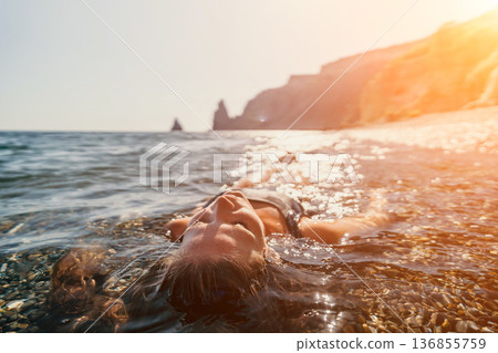 Woman floating relaxation peaceful female enjoying calm ocean waters at a rocky beach under the warm glow of a golden sunset Woman floating relaxation peaceful female enjoying calm ocean waters at a rocky beach under the warm glow of a golden sunset 136855759