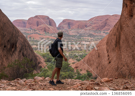 Hiker standing between red domes viewing vast landscape of Kata Tjuta, Australia Hiker standing between red domes viewing vast landscape of Kata Tjuta, Australia 136856095