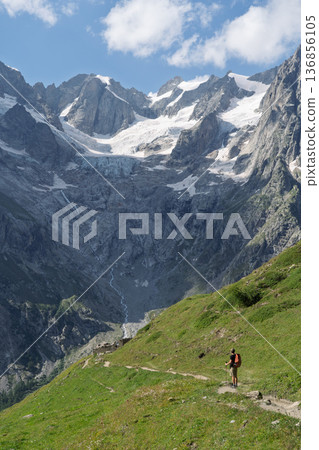 Hiker on Tour du Mont Blanc trail viewing glaciers in Val Ferret, Switzerland 136856105