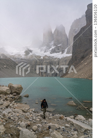 Hiker emerging from water below misty Torres del Paine, Patagonia, Chile 136856110