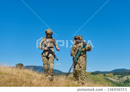 Two Soldiers in Camouflage Patrol Hillside With Sniper and Infantry Rifle During Military Training 136856553