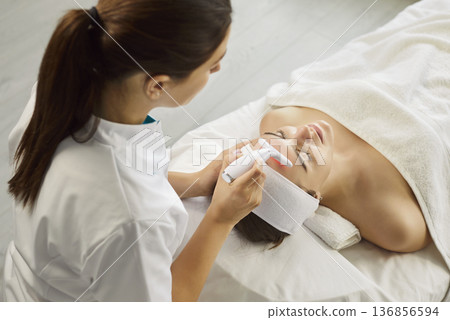 Young woman receiving ultrasound facial cleaning procedure lying on couch in beauty clinic. Young woman receiving ultrasound facial cleaning procedure lying on couch in beauty clinic. 136856594