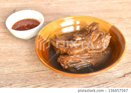 boiled slice duck foot and wing in black soybean herb soup in bowl dipping spicy sour chili sauce boiled slice duck foot and wing in black soybean herb soup in bowl dipping spicy sour chili sauce 136857567