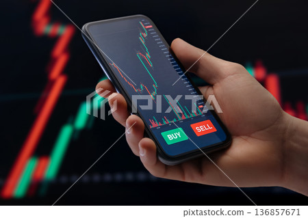 trader using a mobile trading platform application on smartphone trader using a mobile trading platform application on smartphone 136857671