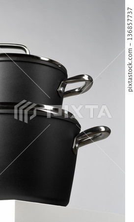 Black cooking pots are stacked on a white surface with gray background in a kitchen setting Black cooking pots are stacked on a white surface with gray background in a kitchen setting 136857737