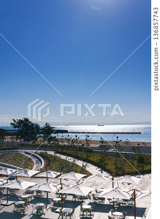 A sunny day with a seaside terrace and white parasols A sunny day with a seaside terrace and white parasols 136857743